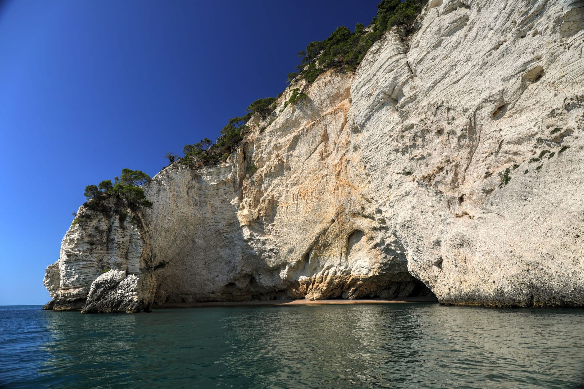 La vieille ville blanche de Vieste perchée sur son promontoire et le monolithe Pizzomunno